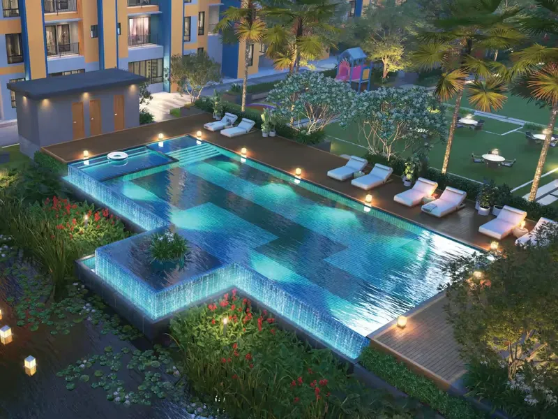 Infinity pool and kids' pool lit at night with deck loungers